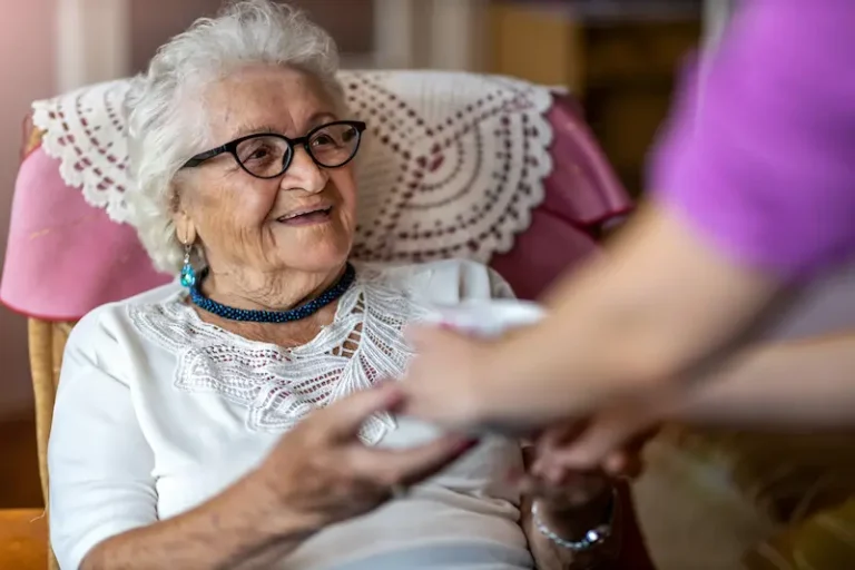 The Gardens of Buda | Senior woman receiving tea from a care taker